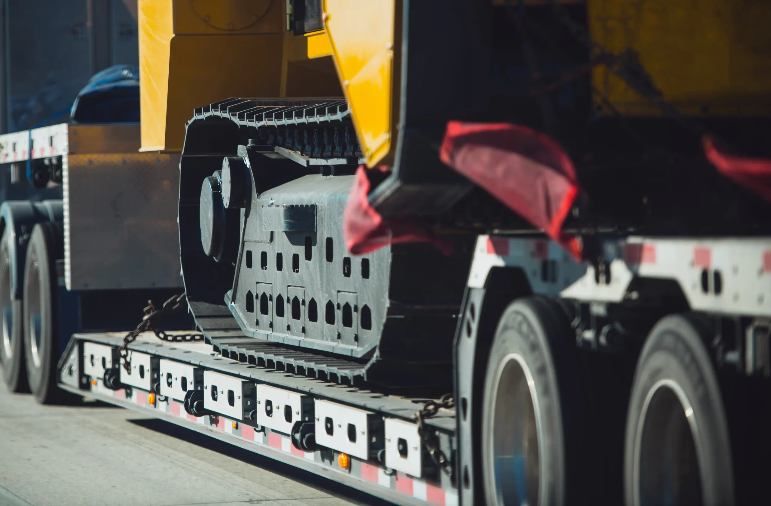 Close-up of heavy-duty construction machinery on a flatbed trailer. As a nationwide drive-away company, BlackBee Logistics is commited to safe and reliable transport.